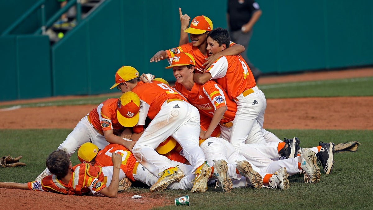 Louisiana's Stan Wiltz embracing Peyton Spadoni (6) as they jump on top of Jeffrey Curtis and Conner Perrot (9) celebrating the 8-0 win against Curacao in the Little League World Series championship game. (AP Photo/Tom E. Puskar)
