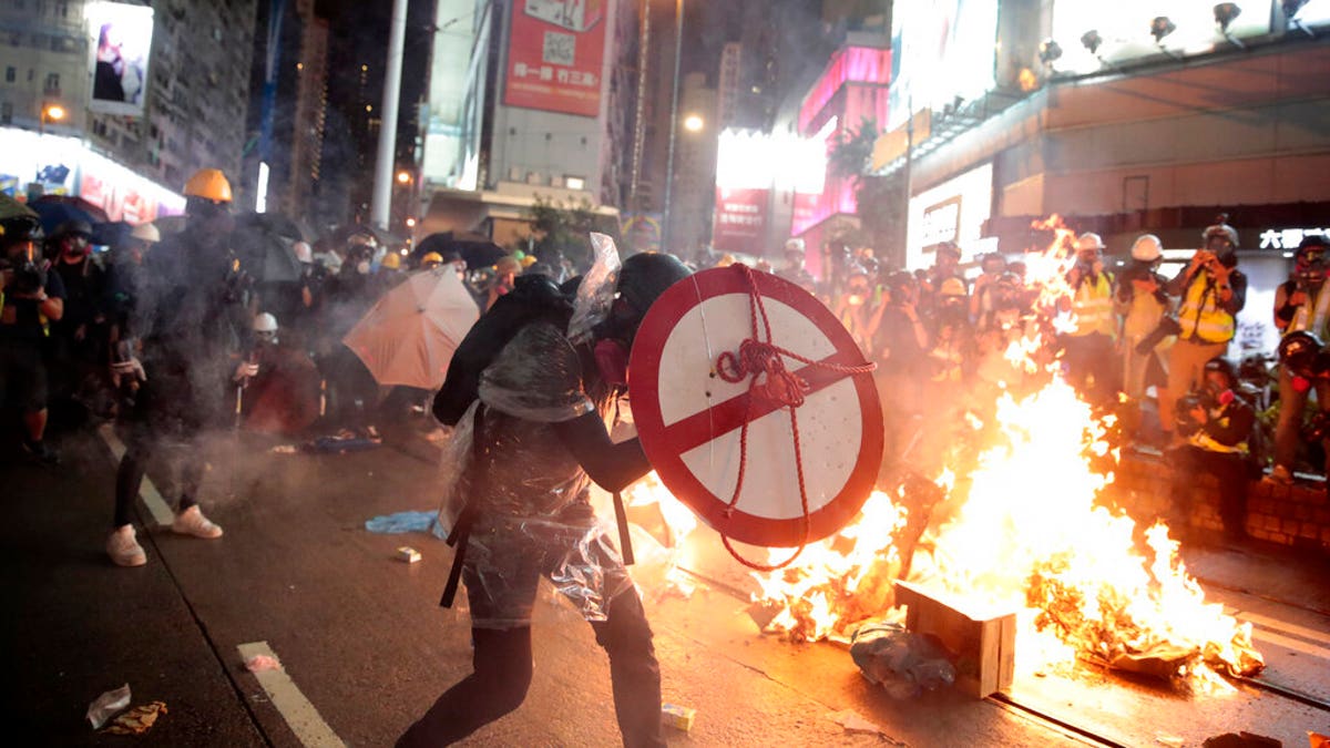 A protestor uses a shield to cover himself as he faces policemen in Hong Kong, Saturday, Aug. 31, 2019. Protesters and police are standing off in Hong Kong on a street that runs through the bustling Causeway Bay shopping district. (AP Photo/Jae C. Hong)