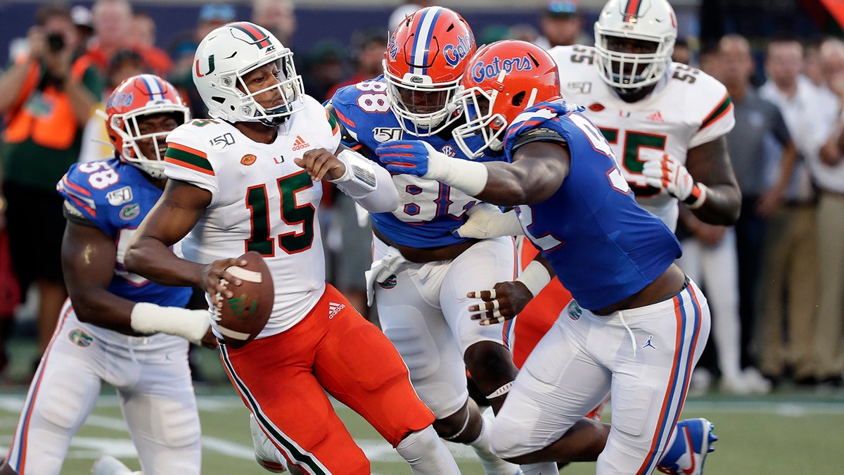 Miami quarterback Jarren Williams (15) tries to scramble before he is sacked by Florida linebacker Jonathan Greenard, left, defensive lineman Adam Shuler, center, and defensive lineman Jabari Zuniga, right, during the first half of an NCAA college football game Saturday, Aug. 24, 2019, in Orlando, Fla. (AP Photo/John Raoux)