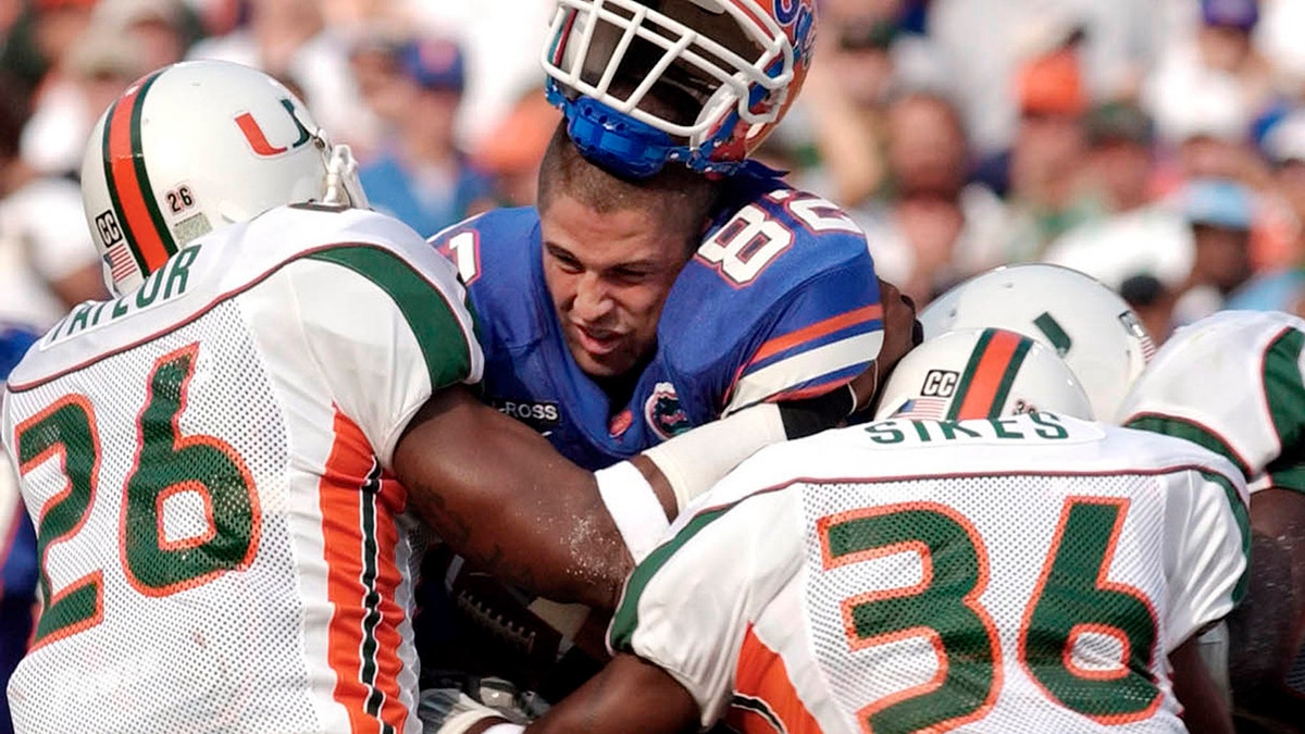 FILE - In this Sept. 7, 2002 file photo, Florida's tight end Aaron Walker, (82) loses his helmet as he is hit by Miami defenders Sean Taylor (26) and Maurice Sikes (36) during the first quarter of a NCAA college football game, in Gainesville, Fla. (AP Photo/Phelan Ebenhack, File)