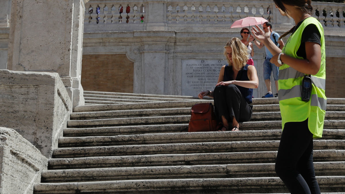A police officer asks a woman not to sit on the Spanish Steps, in Rome, Wednesday, Aug. 7, 2019.