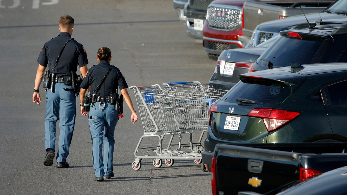 Police officers walk by shopping carts at the scene of a mass shooting at a shopping complex Sunday, Aug. 4, 2019, in El Paso, Texas.