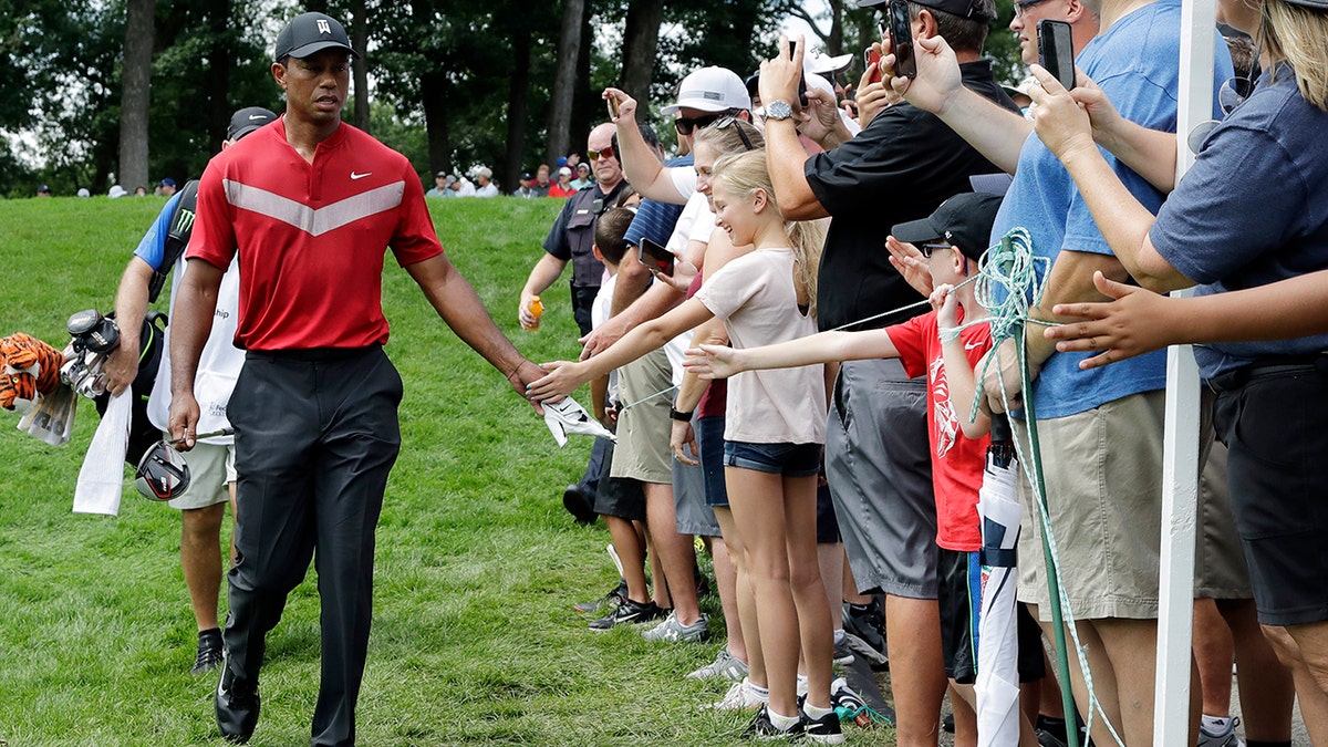 Tiger Woods, left, greets fans as he walks to the 14th fairway after hitting his tee shot during the final round of the BMW Championship golf tournament at Medinah Country Club, Sunday, Aug. 18, 2019, in Medinah, Ill. (AP Photo/Nam Y. Huh)