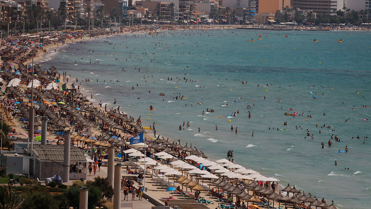 Tourists and beachgoers are seen along the beach outside of the village of El Arenal, in Palma de Mallorca, on Aug. 6, 2019.