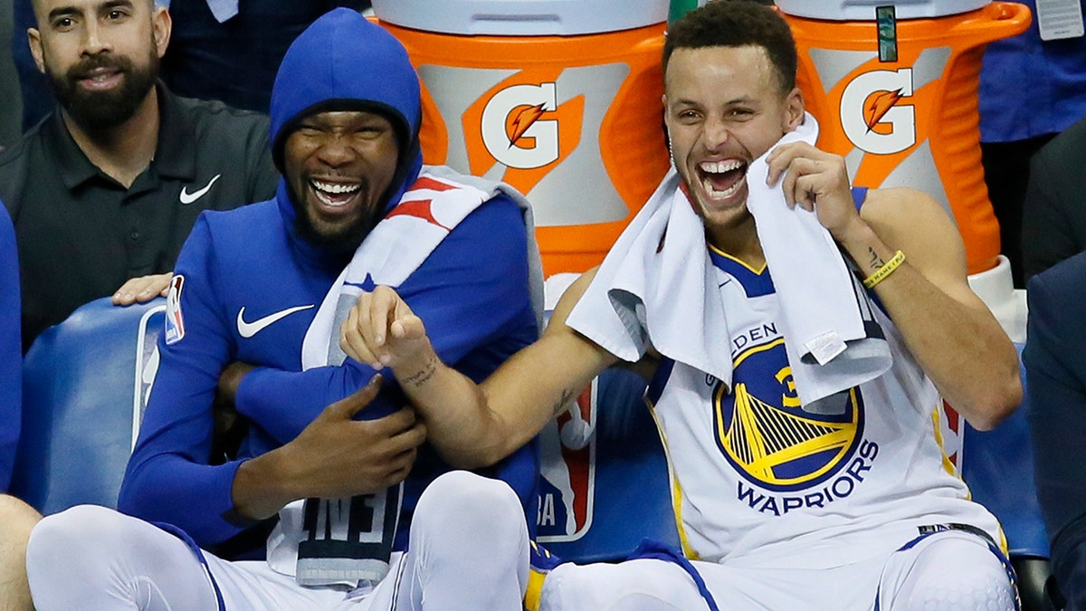 FILE - In this Nov. 22, 2017, file photo, Golden State Warriors forward Kevin Durant, left, and guard Stephen Curry, right, laugh on the bench during the third quarter of the team's NBA basketball against the Oklahoma City Thunder in Oklahoma City. (AP Photo/Sue Ogrocki, File)