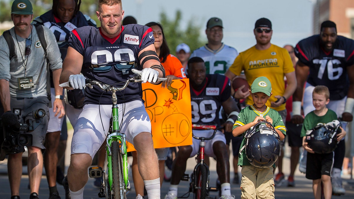 Houston Texans' J.J. Watt rides a bike to a joint NFL football practice between the Texans and the Green Bay Packers Monday, Aug 5, 2019, in Green Bay, Wis. (AP Photo/Mike Roemer)