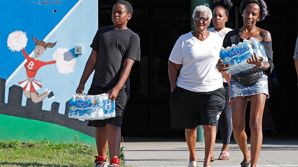 Rahjiah McBride, of Chester, Pa., right, helping her relatives, Newark residents Elnora and Bowdell Goodwin, center and second right, as Goodwin's son pitches in carrying bottled water earlier this month. (AP Photo/Kathy Willens)