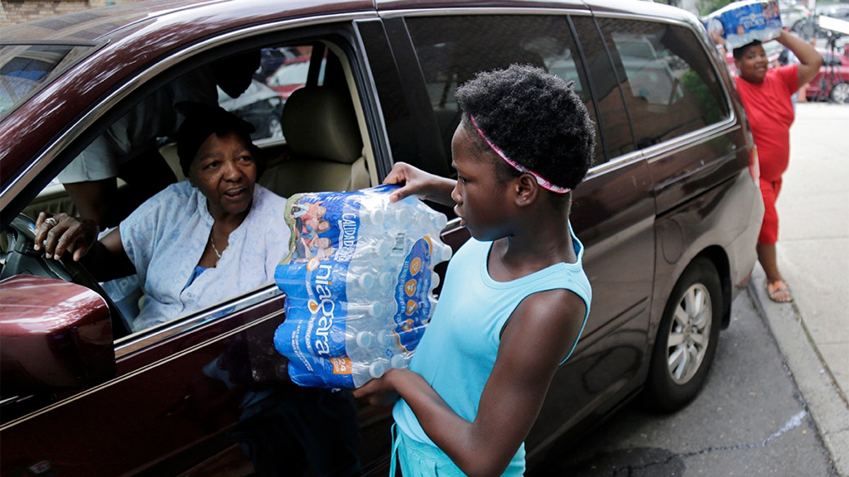 Elaine Younger, 11, and Tahvion Williams, 14, right, loading water in their family's van at the Newark Health Department earlier this month. (AP Photo/Seth Wenig)