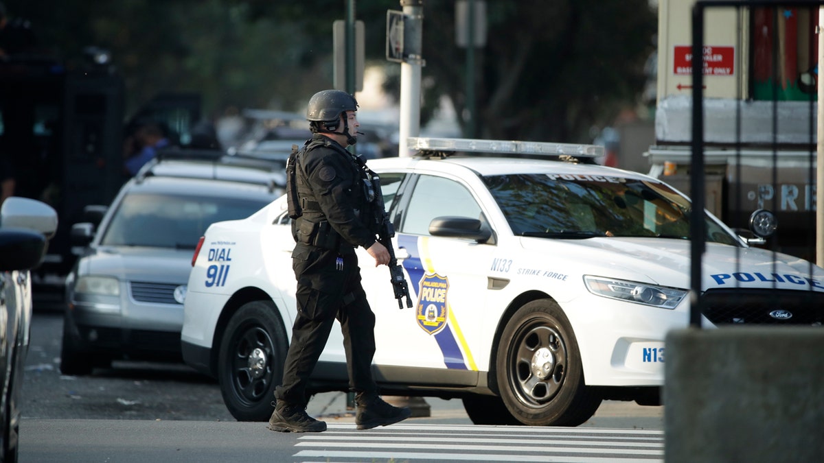 A police officer patrols the block near a house as they investigate an active shooting situation, Wednesday, Aug. 14, 2019, in the Nicetown neighborhood of Philadelphia.