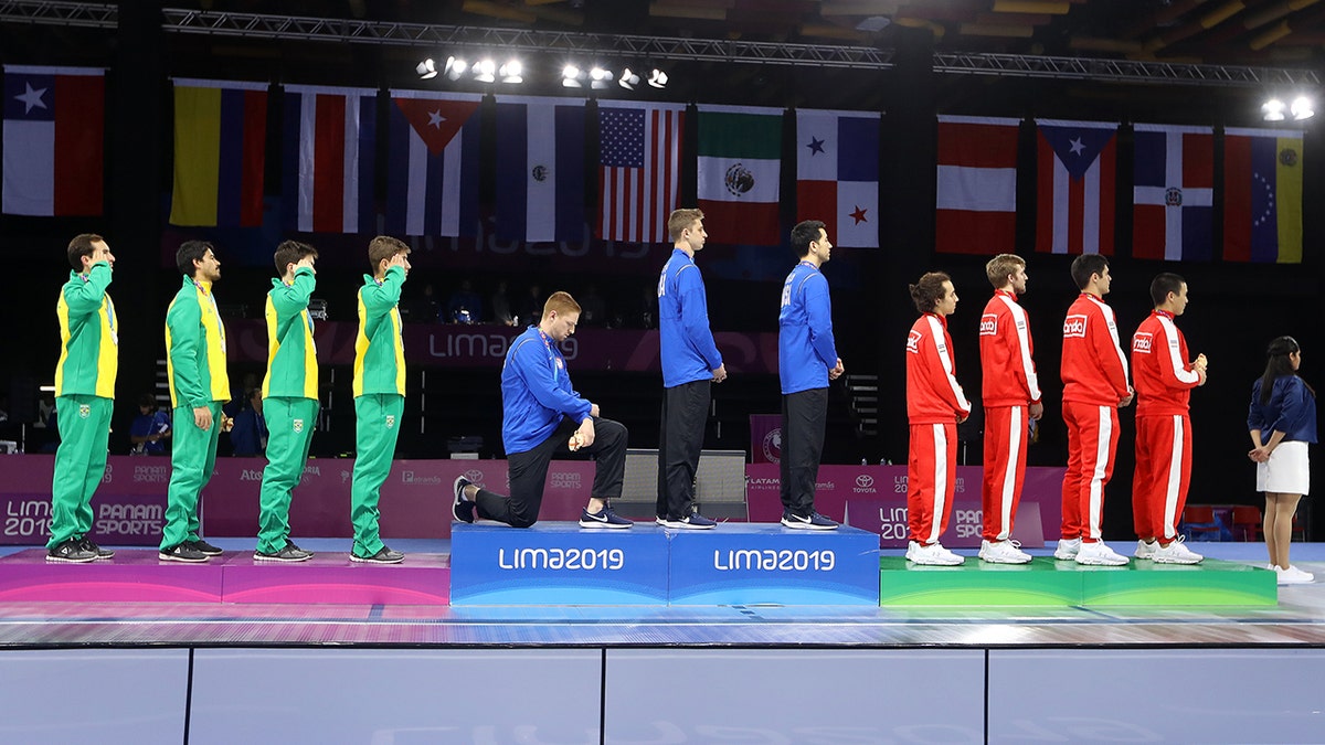 Gold medalist Race Imboden of United States takes a knee during the National Anthem Ceremony in the podium of Fencing Men's Foil Team Gold Medal Match Match on Day 14 of Lima 2019 Pan American Games at Fencing Pavilion of Lima Convention Center on August 09, 2019 in Lima, Peru. (Photo by Leonardo Fernandez/Getty Images)