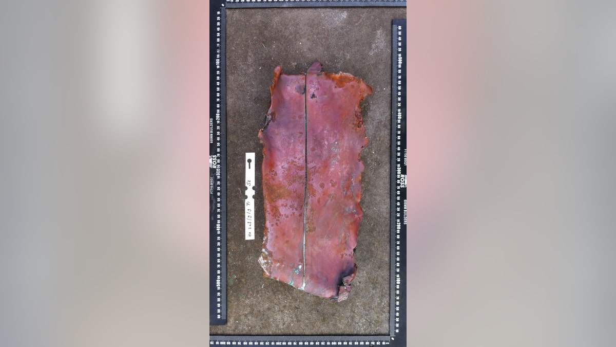 Fragment of a metal composite plate excavated on Sept. 9, 2018. It consists of a layer of copper, backed by a layer of lead. Historical information indicates that the stern post and rudder of Dutch East India Company ships like 'Haarlem' used plates such as this. (©AIMURE/Bruno Werz)