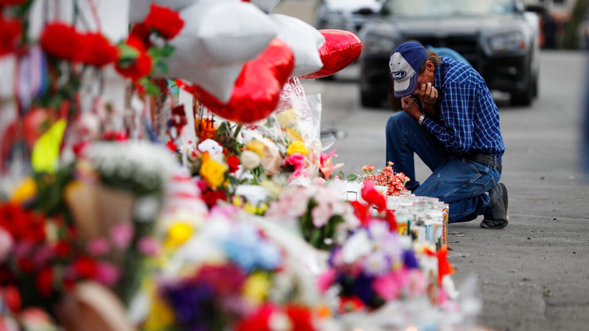 A man cries beside a cross at a makeshift memorial near the scene of a mass shooting at a shopping complex Tuesday, Aug. 6, 2019, in El Paso, Texas. (AP Photo/John Locher)