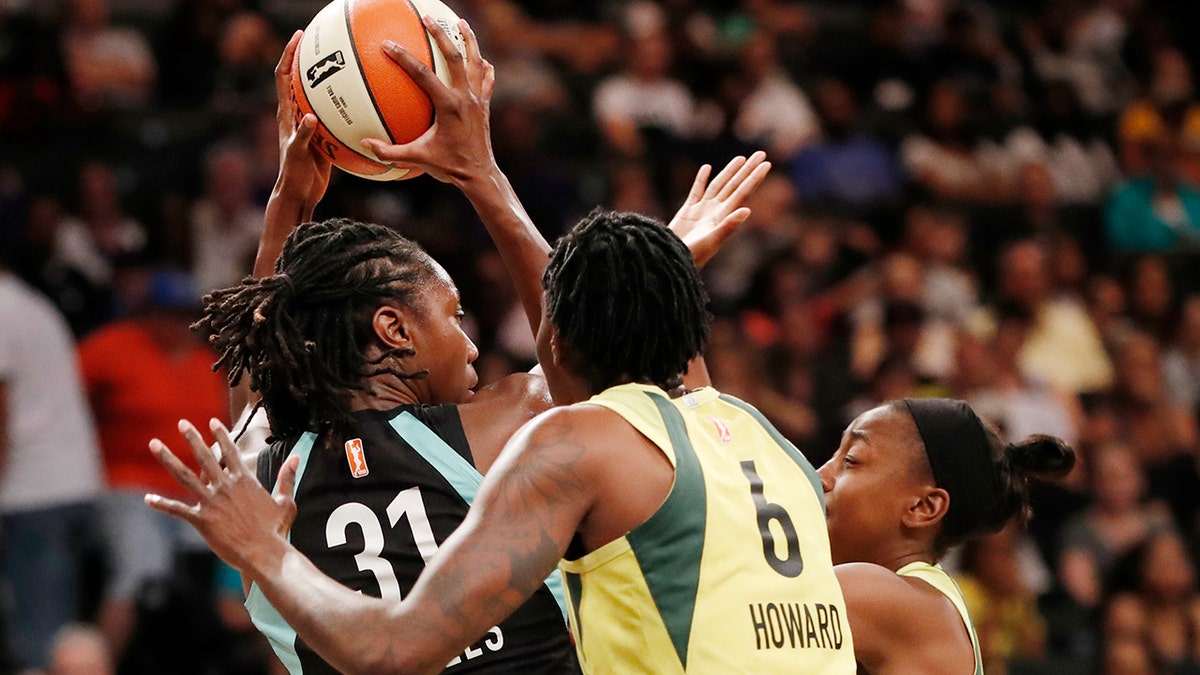 Seattle Storm forward Natasha Howard, right, defends New York Liberty center Tina Charles, left, who looks to pass during the first half of a WNBA basketball game, Sunday, Aug. 11, 2019, in New York. (AP Photo/Kathy Willens)