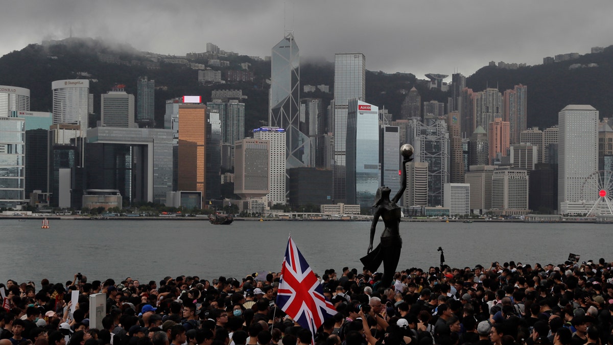 In this Sunday, July 7, 2019, photo, thousands of protesters carrying the British flag march near the harbor of Hong Kong. Hong Kong police on Tuesday confirmed it had received a report on Aug. 9, 2019, about a British foreign ministry employee who has been missing since crossing into China on a business trip.