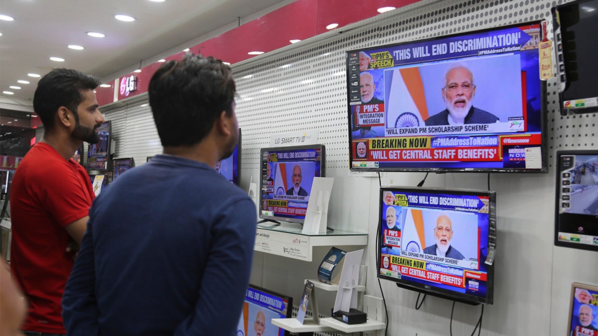 Indians watch Prime Minister Narendra Modi address the nation in an electronics store Thursday. (AP Photo/Channi Anand)