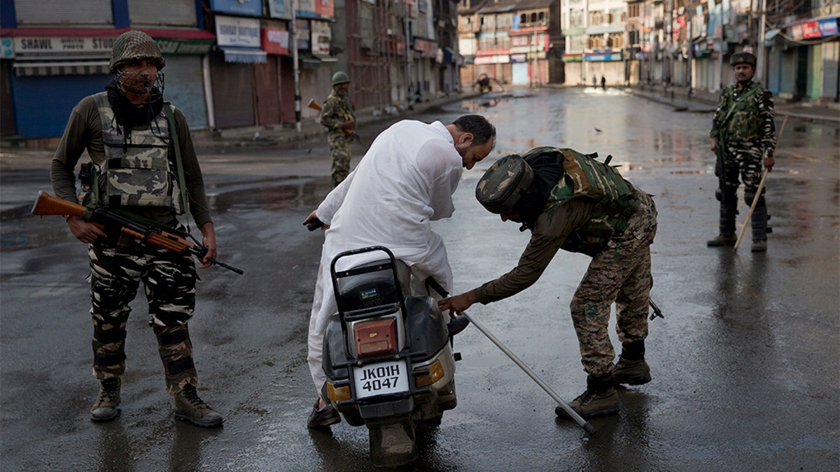 Indian Paramilitary soldiers check the bag of a man riding a scooter during curfew in Indian controlled Kashmir, Thursday, Aug. 8, 2019. (AP Photo/Dar Yasin)