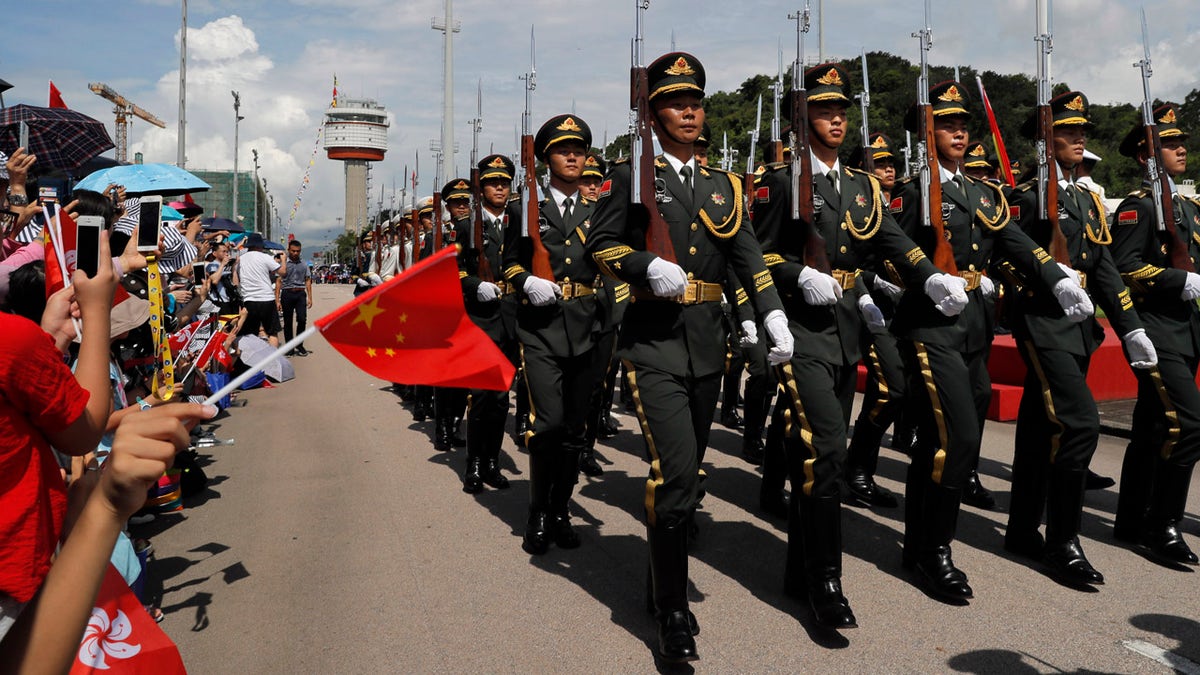 In this June 30, 2019, file photo, Chinese People's Liberation Army (PLA) soldiers take part in a flag raising ceremony during an open day of Stonecutter Island naval base, in Hong Kong, to mark the 22nd anniversary of Hong Kong handover to China.