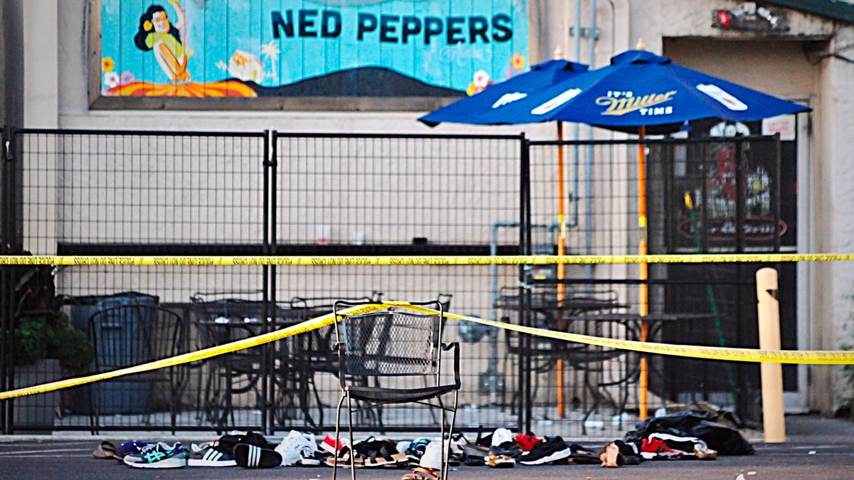 Police tape drapes over a chair near a pile of shoes after a mass shooting in Dayton, Ohio on Sunday, Aug, 4, 2019.