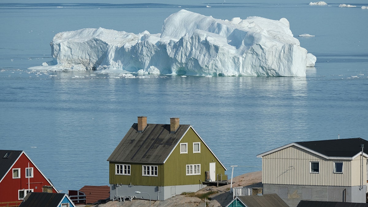 An iceberg floats in Disko Bay behind houses during unseasonably warm weather on July 30, 2019 in Ilulissat, Greenland. (Photo by Sean Gallup/Getty Images)
