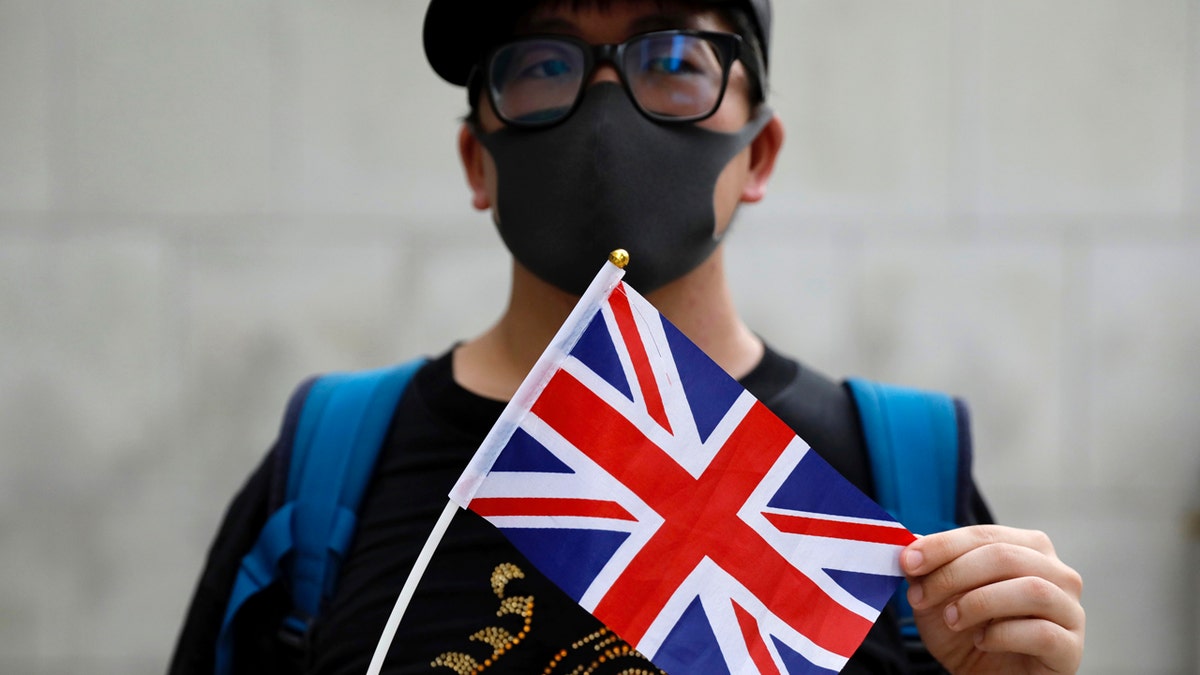 A supporter holds a British flag outside of the British Consulate in Hong Kong during a rally in support of an employee of the consulate who was detained while returning from a trip to China, Wednesday, Aug. 21, 2019. (AP Photo/Vincent Yu)