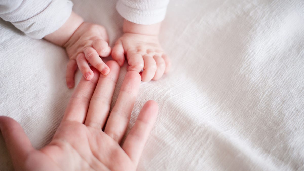 hands of a newborn baby in the mother's fingers