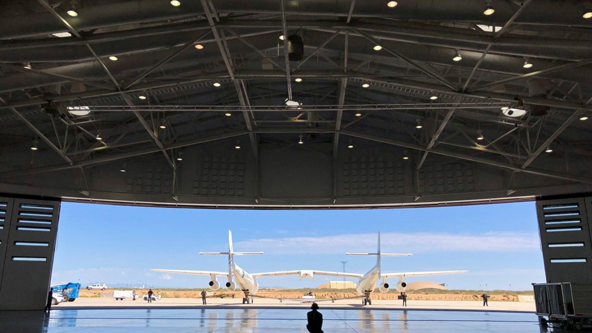 Virgin Galactic ground crew guide the company's carrier plane into the hangar at Spaceport America following a test flight over the desert near Upham, New Mexico, on Thursday, Aug. 15, 2019. The carrier plane is now permanently based at the spaceport after arriving earlier this week. (AP Photo/Susan Montoya Bryan)