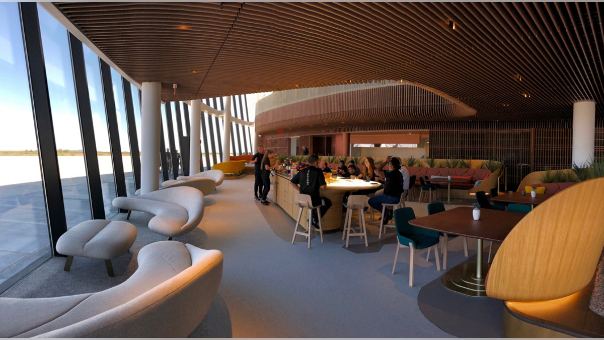 Virgin Galactic employees gather at the coffee bar that serves as the heart of the company's social hub where they will meet with customers and their families at Spaceport America once commercial operations begin near Upham, New Mexico, on Thursday, Aug. 15, 2019. Virgin Galactic unveiled some of the interior spaces of the custom-tailored terminal Thursday, saying the designs are aimed at connecting the customers with operations as they prepare for their suborbital flights. (AP Photos/Susan Montoya Bryan)