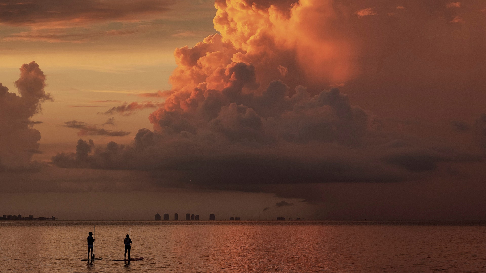 Two paddle boarders stop to watch the sunrise on a stormy morning in Sanibel, Florida, Aug. 15, 2019.