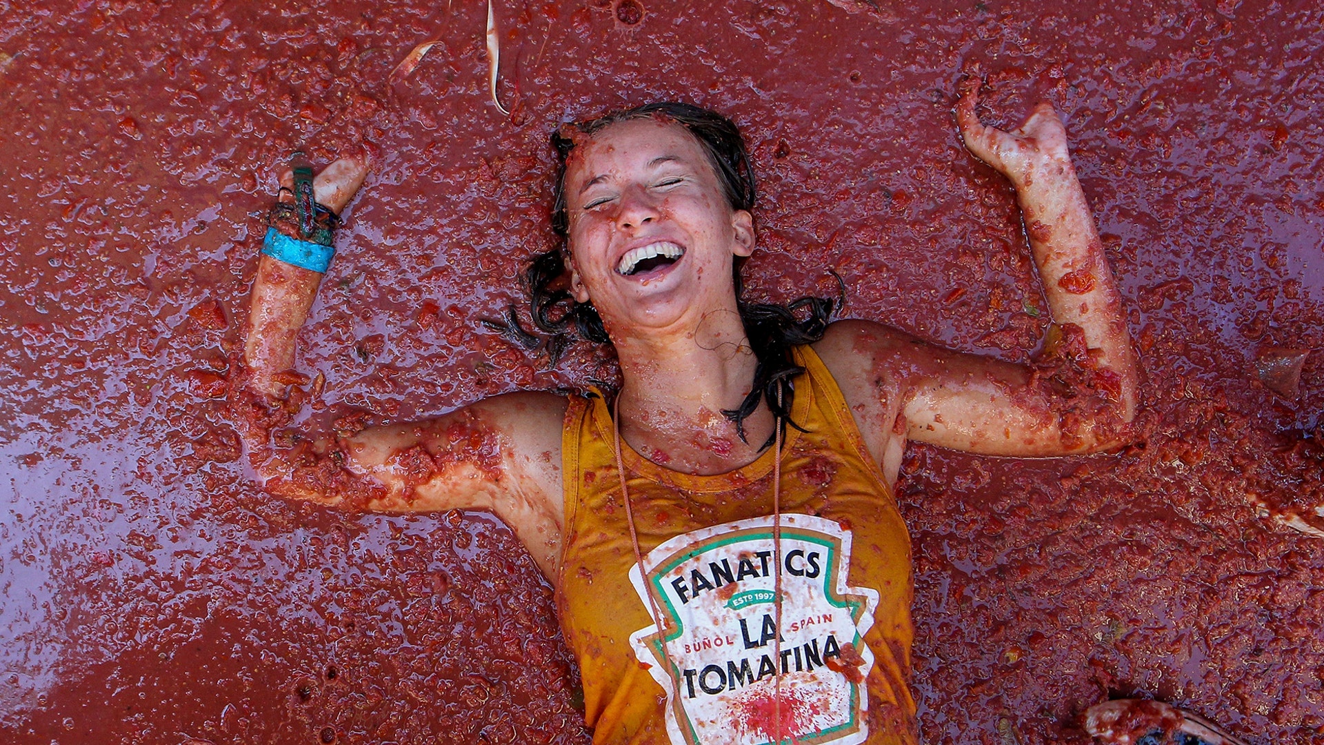 A reveler lies in a puddle of squashed tomatoes during the annual "Tomatina", tomato fight fiesta, in the village of Bunol, near Valencia, Spain, Aug. 28, 2019. 