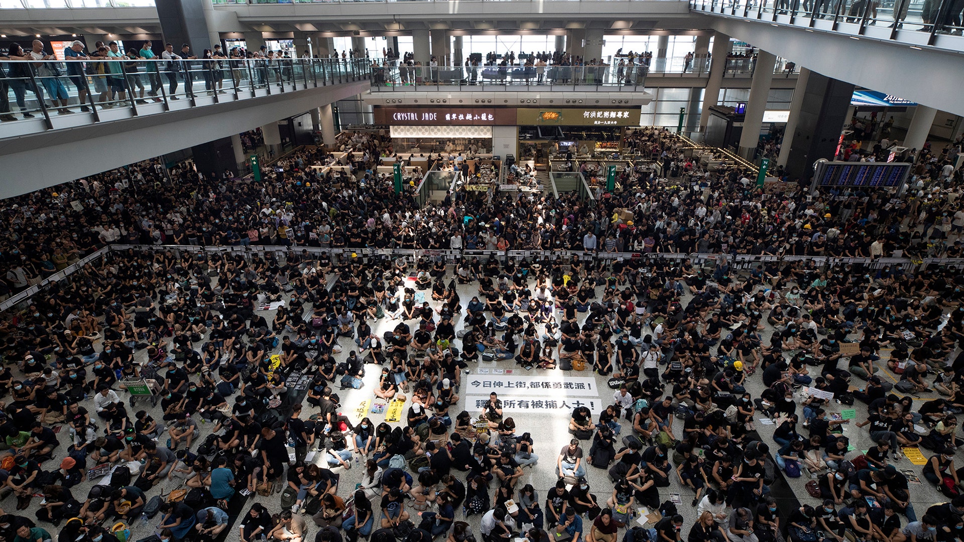 Protesters surround banners that read: "Those on the street today are all warriors!" and "Release all the detainees!" during a sit-in rally at the arrival hall of the Hong Kong International airport in Hong Kong, Aug. 12, 2019.