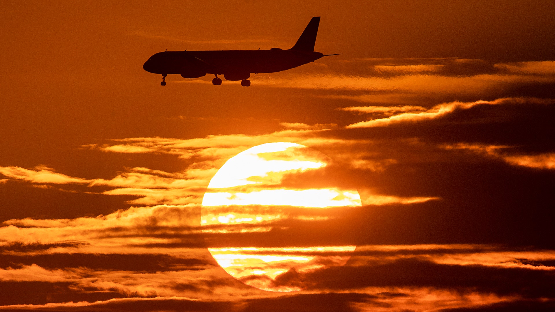 An aircraft passes the sun as it approaches the international airport in Frankfurt, Germany, Aug. 8, 2019.