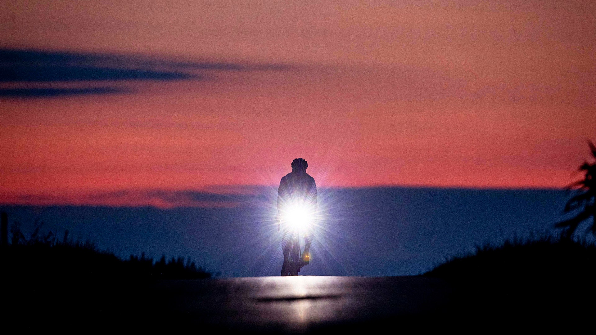 A man rides his bike to work before sunrise on the outskirts of Frankfurt, Germany, Aug. 16, 2019