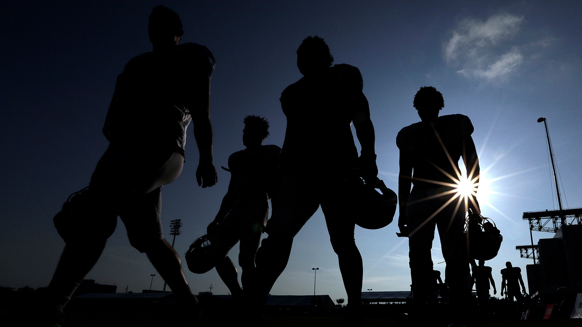 Houston Texans' players walk across a practice field before the start of a joint NFL training camp football practice with the Detroit Lions in Houston, Aug. 15, 2019.