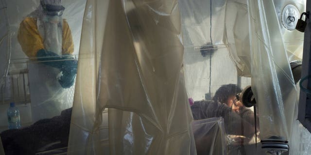 In this Saturday, July 13, 2019 photo, health workers wearing protective gear check on a patient isolated in a plastic cube at an Ebola treatment center in Beni, Congo. On July 17, the World Health Organization declared the Ebola outbreak an international emergency after it spread to eastern Congo's biggest city, Goma.