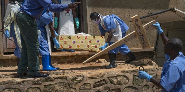 In this Sunday, July 14, 2019 photo, Red Cross workers carry the remains of 16-month-old Muhindo Kakinire from the morgue into a truck as health workers disinfect the area in Beni, Congo. The World Health Organization has declared the Ebola outbreak an international emergency.