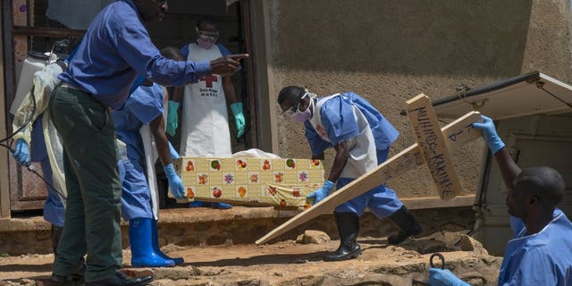 In this Sunday, July 14, 2019 photo, Red Cross workers carry the remains of 16-month-old Muhindo Kakinire from the morgue into a truck as health workers disinfect the area in Beni, Congo. The World Health Organization has declared the Ebola outbreak an international emergency.