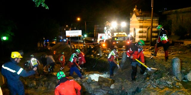 Rescuers work to clear mud from a road in Codesino, near the northern Italian town of Lecco, in the early hours of Wednesday, Aug. 7.