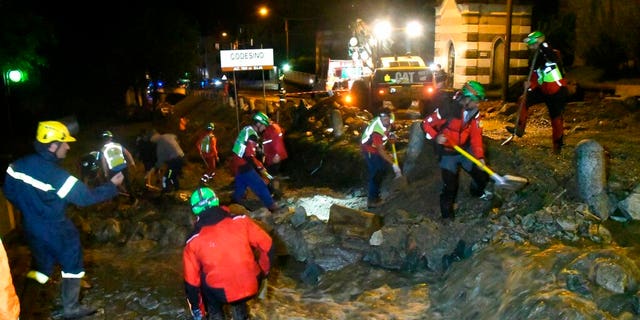 Rescuers work to clear mud from a road in Codesino, near the northern Italian town of Lecco, in the early hours of Wednesday, Aug. 7.