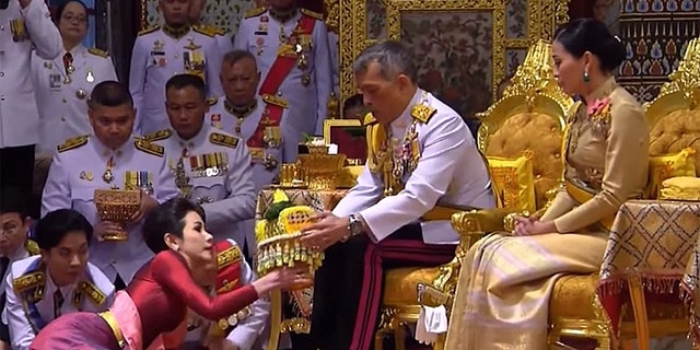 King Maha Vajiralongkorn (center), also known as King Rama X, sits alongside his wife General Suthida Vajiralongkorn (right) as he names Major-General Sineenat Wongvajirapakdi (left) the new Royal Noble Consort.