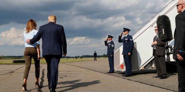 President Donald Trump, with first lady Melania Trump, walks back to Airs Force One after speaking to the media before boarding Air Force One in Morristown, N.J., Sunday, Aug. 4, 2019. (AP Photo/Jacquelyn Martin)