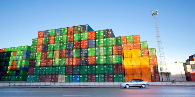 In this Monday, Nov. 24, 2014 file photo, a car drives by stacks of cargo containers at the Port of Antwerp, Belgium. Antwerp police announced Thursday, July 25, 2019 thay they have arrested two men who had called authorities to come rescue them from an overheated container in the port, where they had somehow locked themselves in, allegedly looking for drugs.