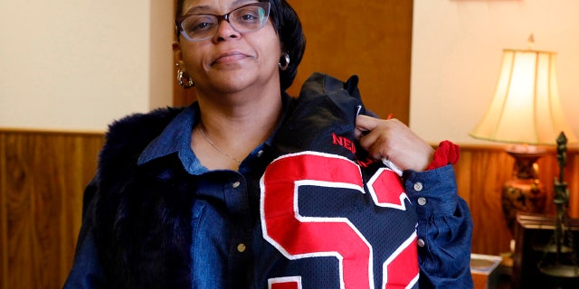 JoAnne Atkins-Ingram drapes her late son's Neptune High School football jersey over her shoulder. (Doug Hood/The Asbury Park Press via AP File)