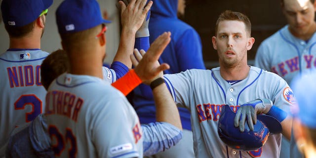 New York Mets' Jeff McNeil, right, celebrates in the dugout after scoring on Robinson Cano's RBI double off Chicago White Sox starting pitcher Dylan Cease, during the sixth inning of a baseball game Thursday, Aug. 1, 2019.