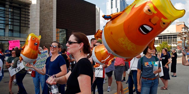 Protesters carry Trump balloons during a "We Stand Up" gathering as they protest a campaign rally by President Donald Trump Thursday, Aug. 1, 2019, in Cincinnati. (AP Photo/Gary Landers)