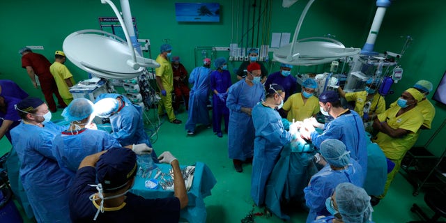 In this Aug. 1, 2019 photograph provided by Action for Defenceless People Foundation, Hungarian doctors Gergely Pataki, left, and Andras Csokay perform separation surgery on Rabeya and Rukaya. (Andras Taborosi/Action for Defenceless People Foundation via AP)