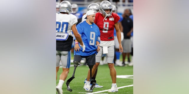 Calder Hodge, 14, of Magnolia, Texas, prepares to run a play with Detroit Lions quarterback Matthew Stafford during an open practice at Ford Field on Friday. Hodge was born without tibia bones but that hasn't stopped him from chasing his dreams of becoming a quarterback. Hodge wants to be the first quarterback with prosthetics. (AP Photo/Carlos Osorio)