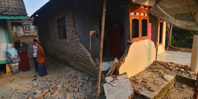 Residents talk near a house damaged in an earthquake in Mandalawangi, Banten province, Indonesia, Saturday, Aug. 3, 2019. (Associated Press)