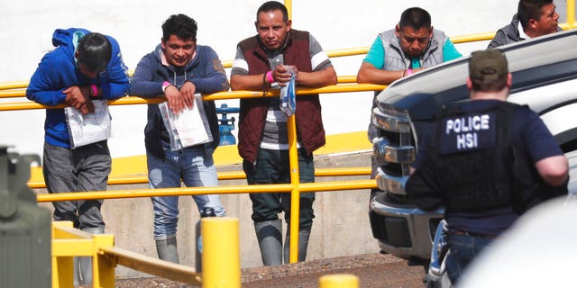 Handcuffed workers await transportation to a processing center following a raid by U.S. immigration officials at Koch Foods Inc., plant in Morton, Miss. U.S. immigration officials raided several Mississippi food processing plants on Wednesday and signaled that the early-morning strikes were part of a large-scale operation targeting owners as well as employees. (AP Photo/Rogelio V. Solis)