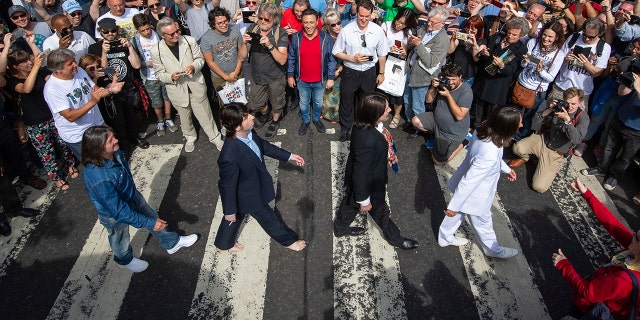 Thousands of fans gather to walk across the Abbey Road zebra crossing, on the 50th anniversary of the famous photo.