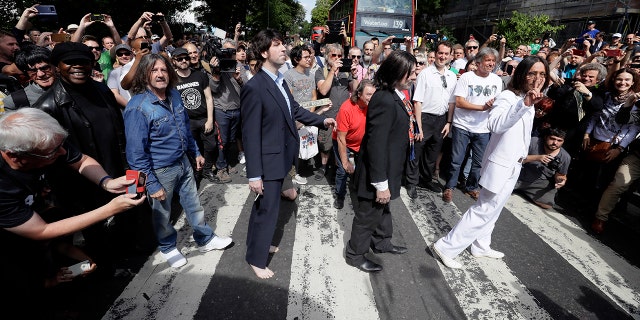 Fans dressed as look-alikes walk across the Abbey Road zebra crossing on the 50th anniversary of British pop musicians The Beatles doing it for their album cover of 'Abbey Road' in St Johns Wood in London, Thursday, Aug. 8, 2019.